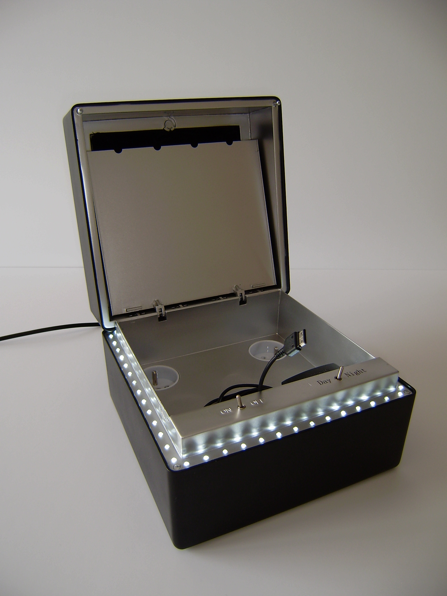 Illuminated technical product prototype in an open enclosure.