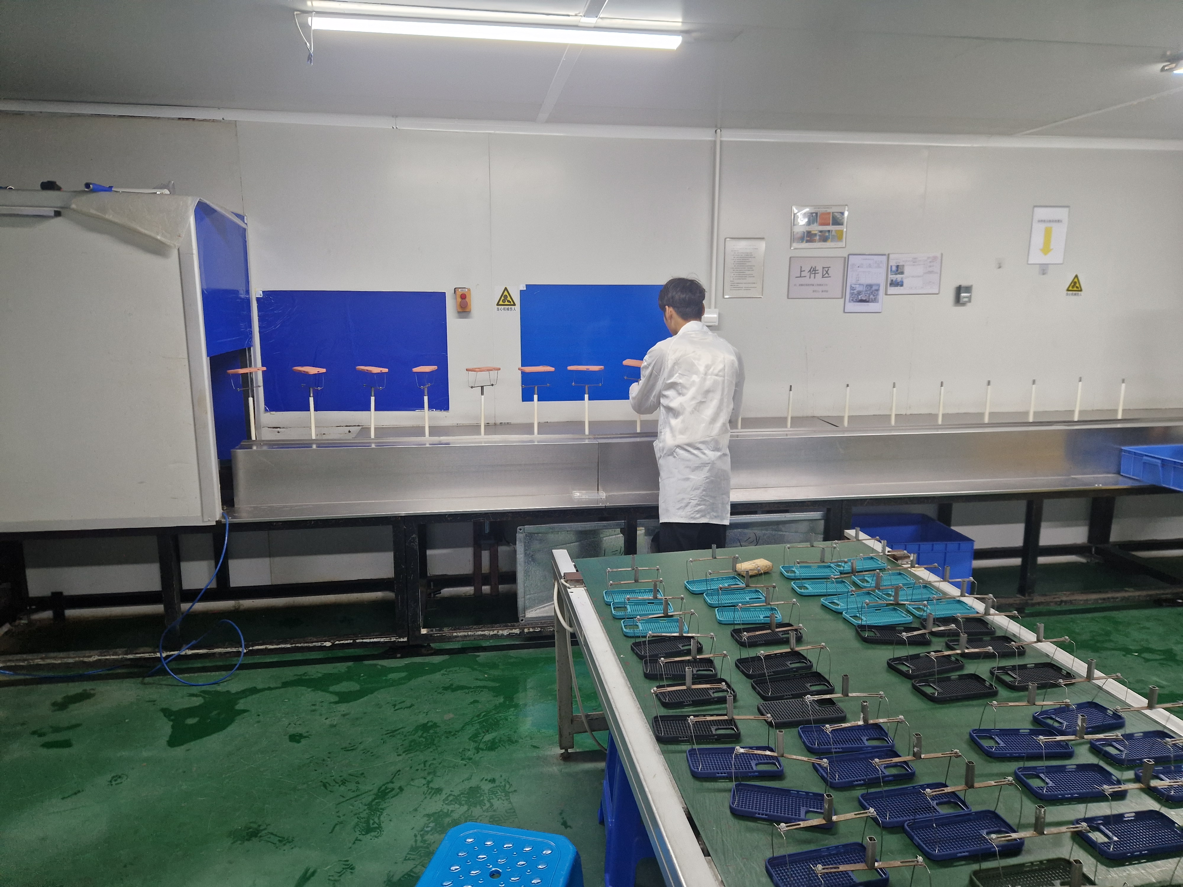 Operator reviewing finished components at an industrial coating and inspection line.